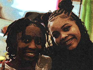 Two african american young girls looking at camera and smiling